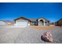 Attractive single-story home featuring a wide driveway, two-car garage, and desert landscaping at 5841 Genoa Ave, Pahrump, NV 89060