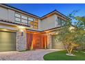 Close-up of the three-car garage with stone accents and a well-maintained lawn at 65 Garibaldi Way, Henderson, NV 89011