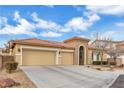 Three-car garage, desert landscaping, and tan exterior at 6545 Candleglade Ct, North Las Vegas, NV 89084