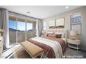 Staged main bedroom featuring balcony access, neutral tones, a plush bed, and contemporary decor at 7044 Stockton Dunes St, North Las Vegas, NV 89084