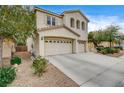 Two-story house with beige exterior, three-car garage, and landscaping at 221 Raptors View Ave, North Las Vegas, NV 89031