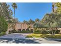 Beautiful home exterior featuring mature landscaping and a circular driveway at 24 Wild Dunes Ct, Las Vegas, NV 89113