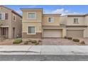 Two-story home featuring tan stucco siding, stone accents, paved driveway, and an attached two-car garage at 5233 Fiery Sky Ridge St, Las Vegas, NV 89148