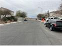 Residential street view with parked cars and distant mountains at 6556 Mount Roy Ln, Las Vegas, NV 89156