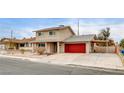 Beige two-story house with red garage door and covered carport at 7232 Raincloud Dr, Las Vegas, NV 89145