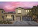 Two-story house with stone accents, solar panels, and a two-car garage at dusk at 7528 Stray Horse Ave, Las Vegas, NV 89113