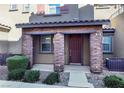 Front entrance of townhome with brick accents and landscaping at 104 Alamere Falls Dr, Las Vegas, NV 89138