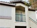 Exterior view of a two-story condo with a balcony, white stucco, and a green metal railing at 5710 E Tropicana Ave # 2122, Las Vegas, NV 89122