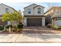 Two-story home with a two-car garage and a brick paved driveway and sidewalk at 365 Andy Wheeler Dr, Henderson, NV 89011