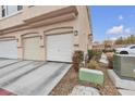 Exterior shot of a townhome with three garage doors and desert landscaping at 9323 Leaping Deer Pl # 102, Las Vegas, NV 89178