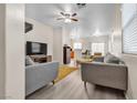 Spacious living area featuring modern sofas, wood-look floors, and open access to the kitchen at 9323 Leaping Deer Pl # 102, Las Vegas, NV 89178