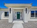 Close-up of the front entrance with a green door framed by pillars and modern lighting fixtures at 2280 S Pampa Ave, Pahrump, NV 89048
