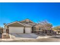 Tan house with a three-car garage and mature tree at 5635 Exotic Rosette Ave, Las Vegas, NV 89139