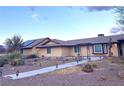 Tan single story home featuring a brown roof, desert landscaping, and an attractive trellis at 7415 Constantinople Ave, Las Vegas, NV 89129