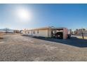 A single-story home with a carport, set on a gravel lot in a desert landscape at 3381 W Simkins Rd, Pahrump, NV 89060