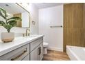 Modern bathroom with gray vanity, gold fixtures, and wood-look tile at 5101 Village Dr, Las Vegas, NV 89142