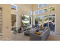 Bright living room features a large gray sofa, media center with two TVs, and large windows overlooking the backyard at 8320 Carmel Ridge Ct, Las Vegas, NV 89113