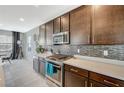 Open kitchen showcasing stainless steel appliances, a mosaic backsplash, and dark wood cabinets at 12898 Slipknot St, Las Vegas, NV 89141