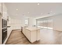 Modern kitchen boasts an island with seating, white cabinets, stainless steel appliances, and wood floors at 65 Ibiza Lake Dr, Henderson, NV 89011