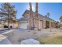 Two-story house with attached garage, palm trees, and gravel landscaping at 1702 La Cruz Dr, Henderson, NV 89014