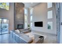 Bright and airy living room with fireplace, featuring high ceilings, a modern sectional and large windows at 2680 Mystere Ct, Las Vegas, NV 89117