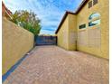 Side yard with brick pavers and a modern black gate at 7874 Clearwood Ave, Las Vegas, NV 89123