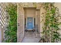 Inviting front entrance with a decorative gate, climbing vines, and a blue front door with a wreath at 1104 Bower Basin St, Las Vegas, NV 89144