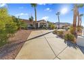 Front view of a single story home with a long driveway and desert landscaping on a sunny day at 321 E Middleton Dr, Henderson, NV 89015