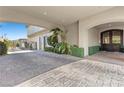 Covered driveway featuring detailed brickwork, lush greenery, and convenient access to the home's entrance at 10000 Cresent Mesa Ln, Las Vegas, NV 89145