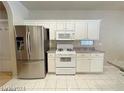 Modern kitchen featuring stainless steel appliances, white cabinetry, and sleek countertops with tile floors at 7633 Winterthur Ct, Las Vegas, NV 89129