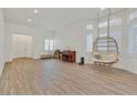 Bright living room with a hanging chair, wood floors and many windows at 9668 Padre Peak Ct, Las Vegas, NV 89178