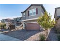 Two-story house with gray siding, brown garage door, and landscaping at 9217 Quartz Hills Ave, Las Vegas, NV 89178