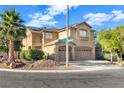 Two-story house with tan siding, two-car garage, and palm trees at 10636 Amblewood Way, Las Vegas, NV 89144