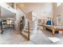 Elegant entryway with a curved staircase and views into the living room at 6165 Smarty Jones Ave, Las Vegas, NV 89131