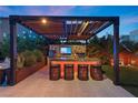 Outdoor kitchen and bar area with a pergola and modern amenities at 8620 Grove Mill Ct, Las Vegas, NV 89139