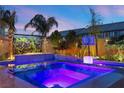 Inviting pool area featuring a spa, lush landscaping, and ambient lighting for evening enjoyment at 8620 Grove Mill Ct, Las Vegas, NV 89139