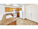 Kitchen with wood cabinets, tile floors, and white appliances at 6149 Ethel May Ave, Las Vegas, NV 89108