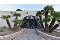 Elegant home entrance with palm trees and a unique arched gate at 7045 Edna Ave, Las Vegas, NV 89117