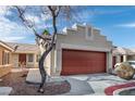 Home exterior featuring a two-car garage and desert landscaping under a partly cloudy sky at 1069 Appleblossom Time Ave, North Las Vegas, NV 89031