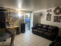Cozy living room with neutral walls, tile floors, dark leather sofa, and decorative wall art at 1901 Belmont St, North Las Vegas, NV 89030