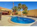 An outdoor swimming pool has tropical landscaping, including palm trees and a covered outdoor seating area at 2410 Doherty Way, Henderson, NV 89014