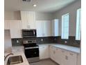Modern kitchen with white cabinets, hexagonal backsplash, and stainless steel appliances at 353 Ukelele Pl # Lot 149, Henderson, NV 89015
