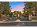 Gated entrance to a private community framed by mature trees, block walls, and lush landscaping at 5555 W Desert Inn Rd, Las Vegas, NV 89146