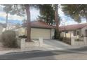 Charming single-story home with a two-car garage, a red tile roof, mature trees, and a well-maintained front yard at 705 Thousand Oaks Dr, Las Vegas, NV 89123