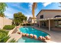 Resort-style pool with stone accents surrounded by lush landscaping and a covered patio at 9843 Frosty Canyon Ct, Las Vegas, NV 89183