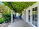 Covered patio with seating area, lush greenery, and access to the backyard at 5880 W Oquendo Rd, Las Vegas, NV 89118