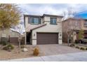 Beige two-story home featuring a brown two-car garage, a brick driveway and desert landscaping at 2240 Sky Island Dr, Henderson, NV 89002