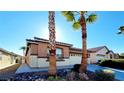 Front view of a tan house with palm trees and a two-car garage at 3317 Barada Heights Ave, North Las Vegas, NV 89081