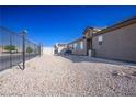 Gravel side yard with a black metal fence and a bench at 4314 Flaming Ridge Trl, Las Vegas, NV 89147