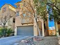 Attractive townhome with two-car garage, complemented by desert landscaping and a clear blue sky at 10840 Holmfield St, Henderson, NV 89052
